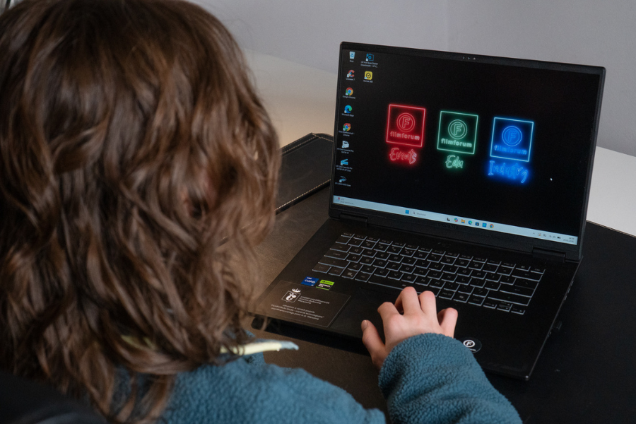 Osoba pracuje przy laptopie z grafiką FILMFORUM, wykorzystując sprzęt zakupiony w ramach projektu wsparcia technologicznego.