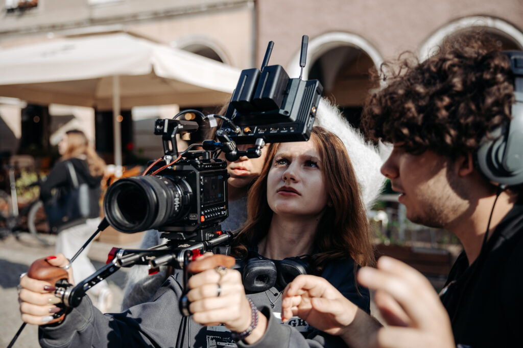 Warsztaty filmowe w praktyce: uczestniczka z kamerą na planie zdjęciowym.